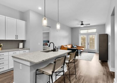 An open-concept kitchen and living room with white walls, counters, and cabinets.