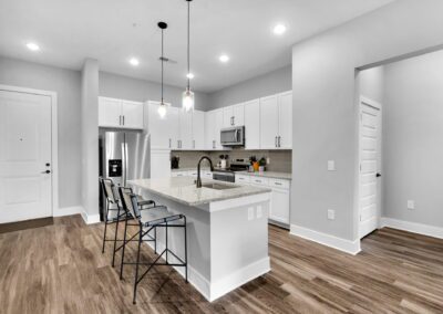 A clean white kitchen with stainless steel appliances and a spacious island in the center.