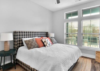 A rustic bedroom with large windows showing the balcony outside.