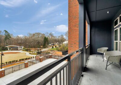 A balcony with rattan patio furniture overlooking a grassy field