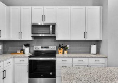 A clean white kitchen with stainless steel glass-top stove and mounted microwave