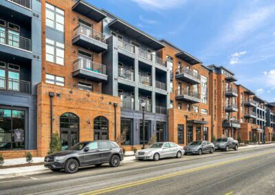 The streetside view of the Mill One apartment buildings. The buildings alternate brick and blue paint facades, and each unit has a balcony.