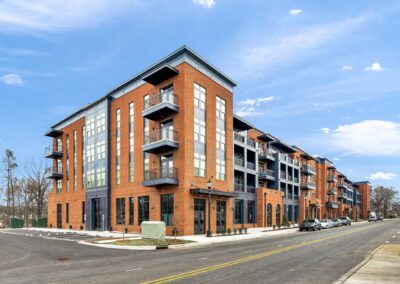 The street corner of the Mill One apartment buildings. The buildings alternate brick and blue paint facades, and each unit has a balcony.